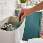 Food coloring being added to a toilet tank for a simple toilet leak test.