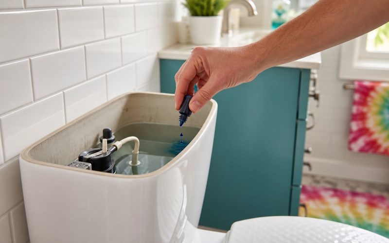 Food coloring being added to a toilet tank for a simple toilet leak test.