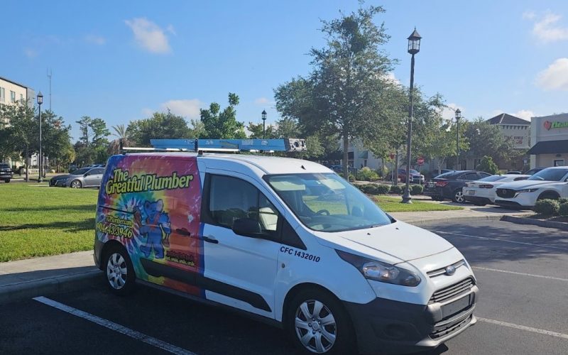 Colorful tie-dye wrapped plumber van parked in Southside Jacksonville shopping center with "The Greatful Plumber" branding