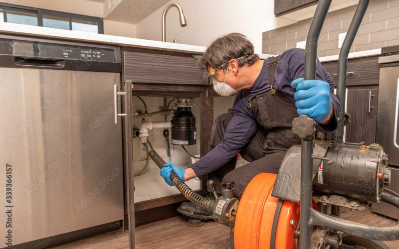 Pro Plumber with Facemask Cleaning Drain